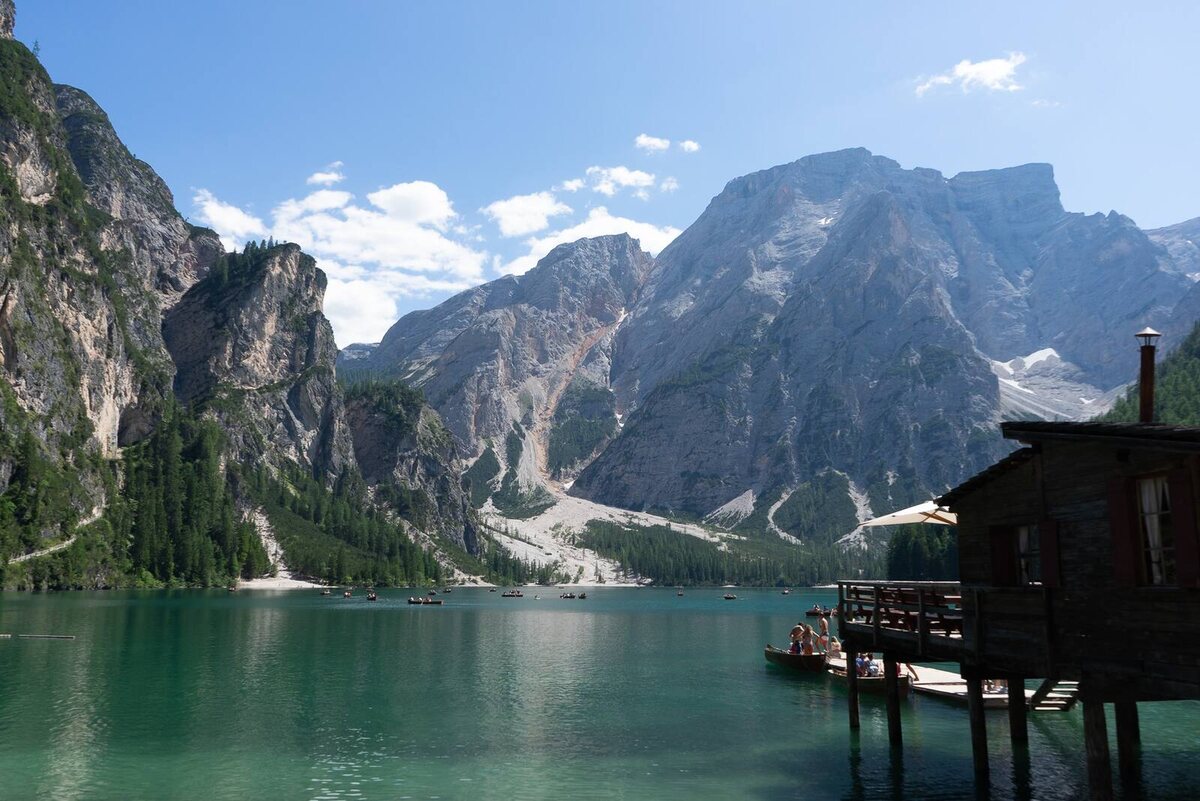 Originalfoto: Bootshaus am Pragser Wildsee im Sommer mit Badegästen und Ruderbooten, Juli 2019