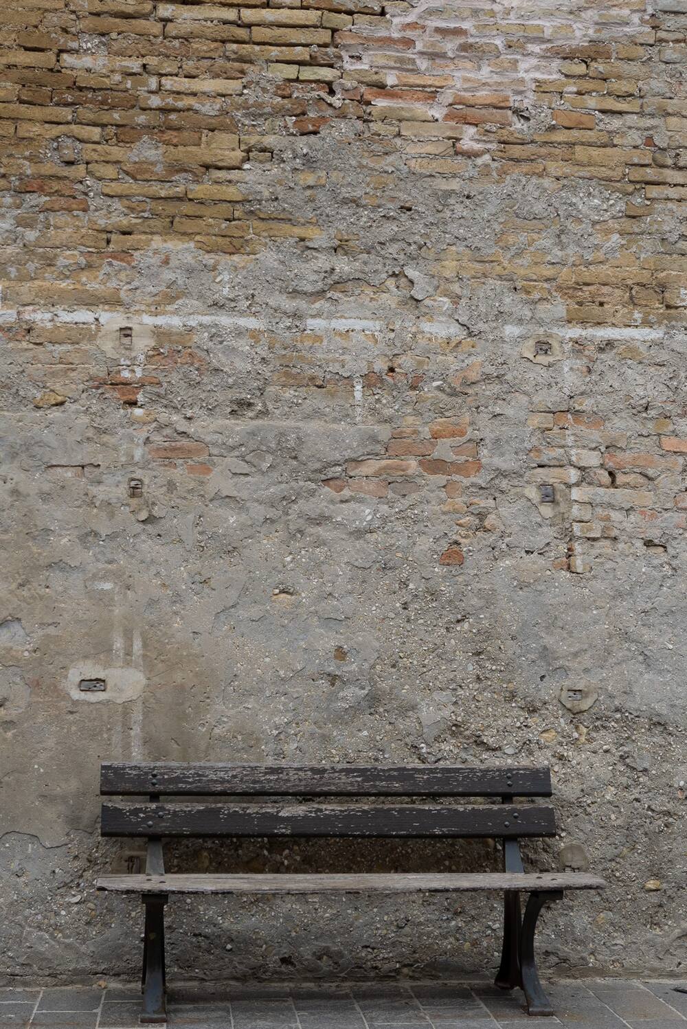 Holzbank vor alter Mauer im Original, flach und grau