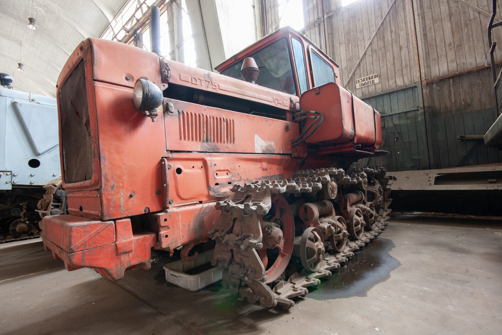 Roter Kettentraktor mit der Aufschrift DT 75 in einer Halle, Raupenlaufwerk im Vordergrund